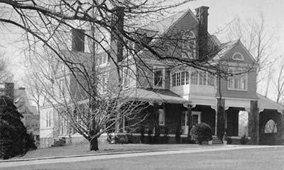 medium-sized tree stands bwteen the mansion and driveway