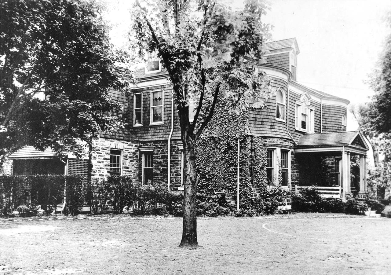view from yard of large Queen Anne house, stone first floor, shingles on second and third