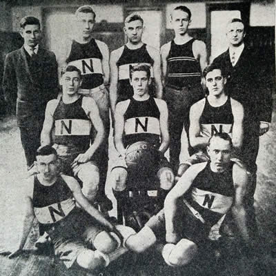 team in uniforms posed in three rows; middle man holds basketball