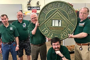 fuive nmen hold up a circular sign that says Ricklin's 1913-2013