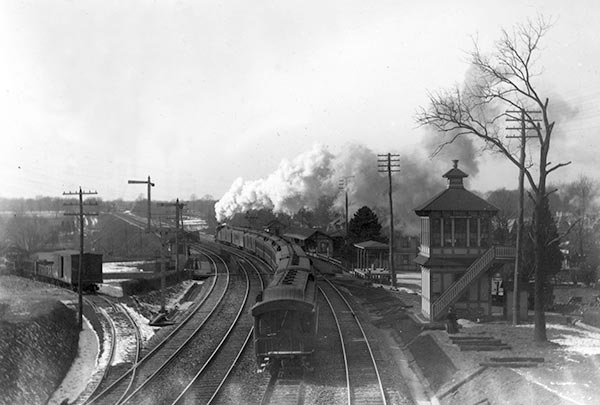 A smoking train pulls past Narberth station heading towards Wynnewood