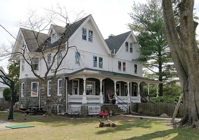 A three-story twin house, first story stone, white frame above.